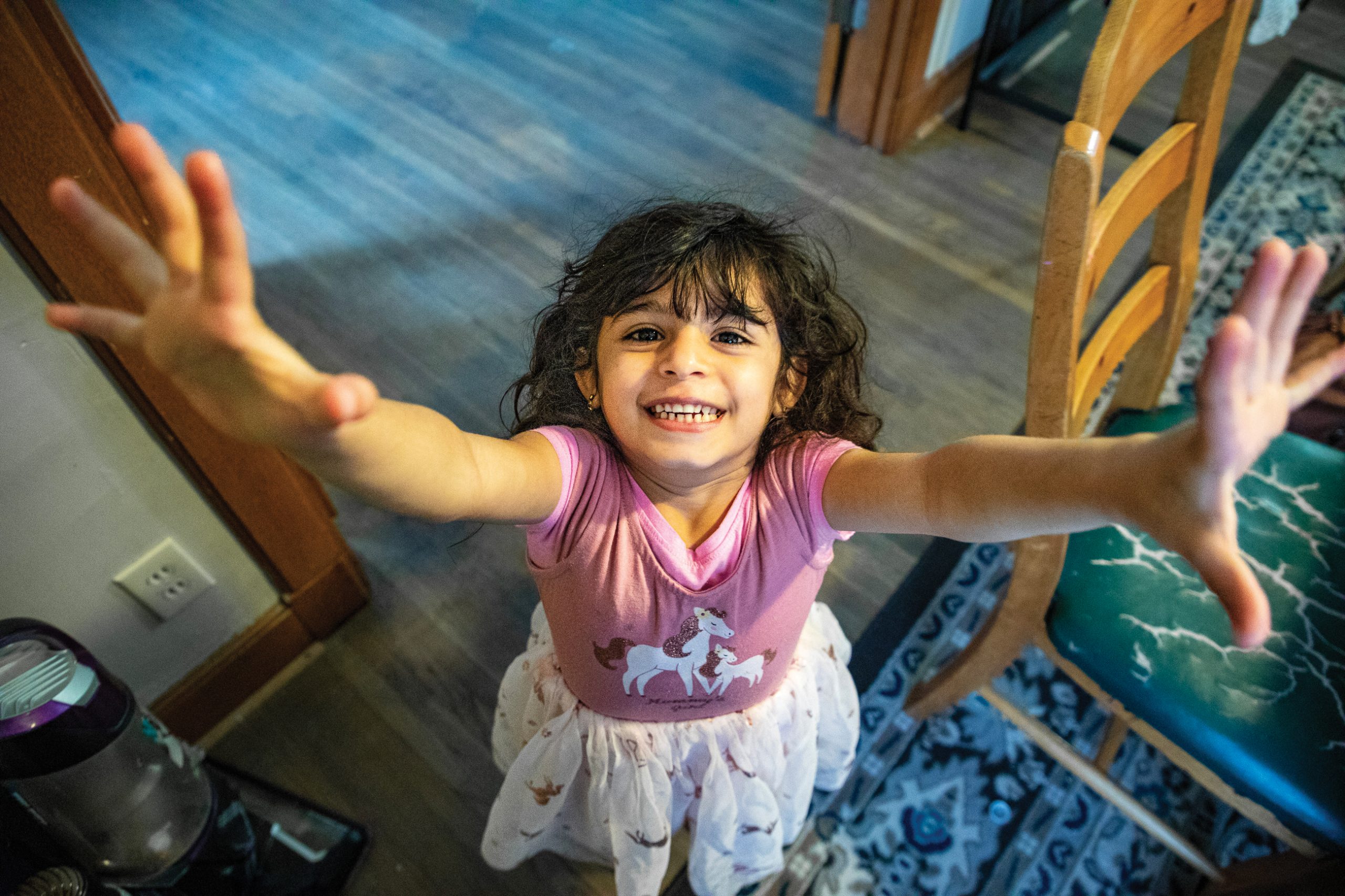 A young girl smiling and reaching out
