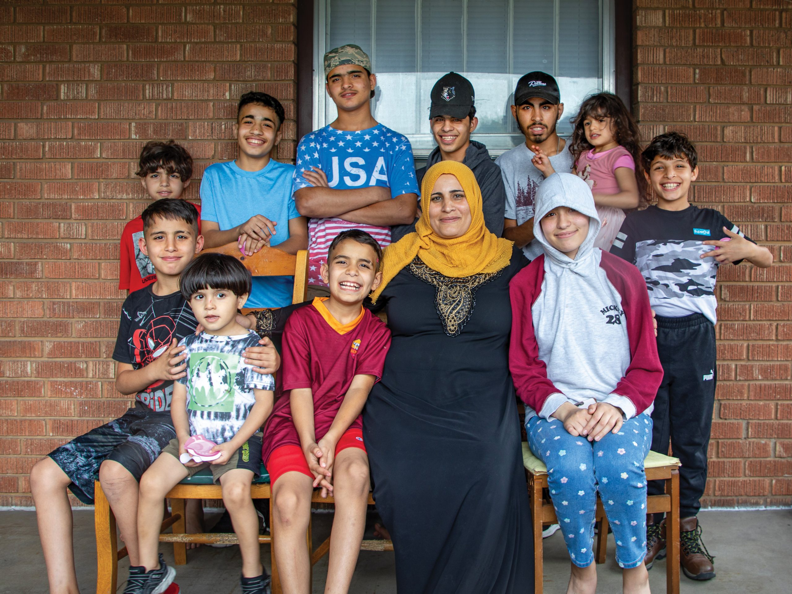 A mother and her 11 children sit on a bench, smiling