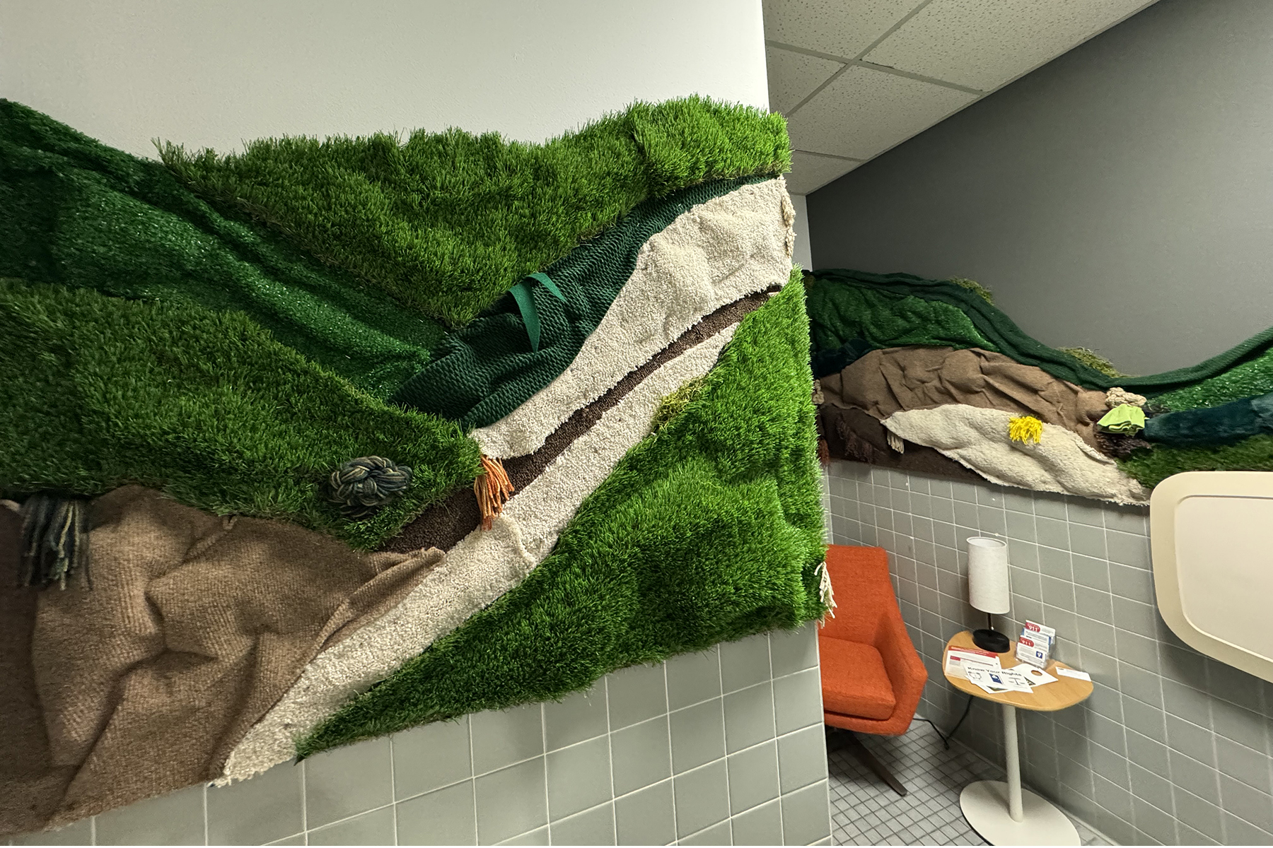 Green, yellow and beige texiles are sculpted into a prairie landscape in the Ulrich lobby restroom.
