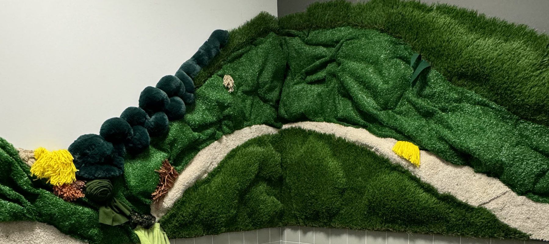 Green, yellow and beige texiles are sculpted into a prairie landscape in the Ulrich lobby restroom.