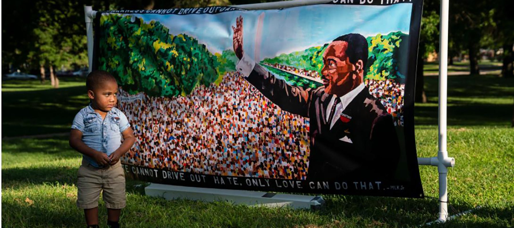A little boy looks at a banner featuring a picture of Martin Luther King.