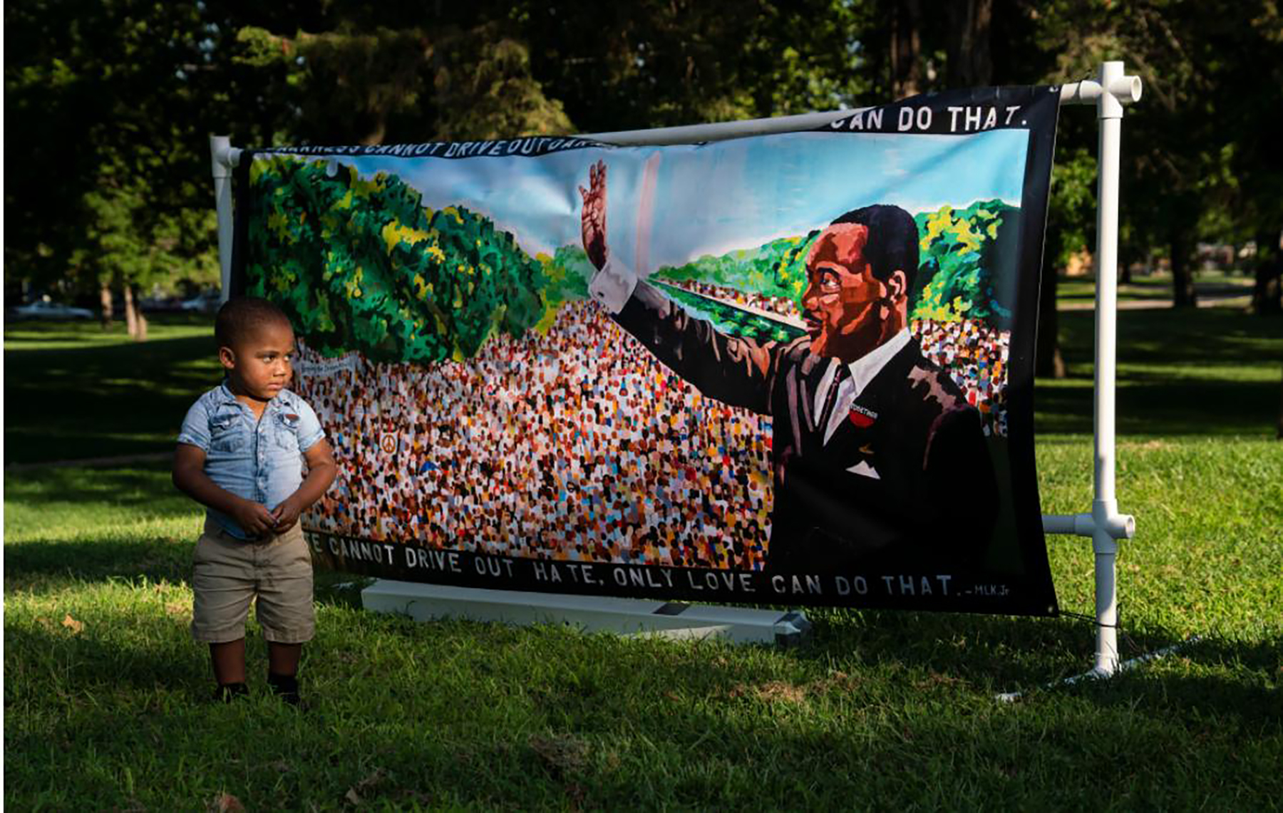 A little boy looks at a banner featuring a picture of Martin Luther King.