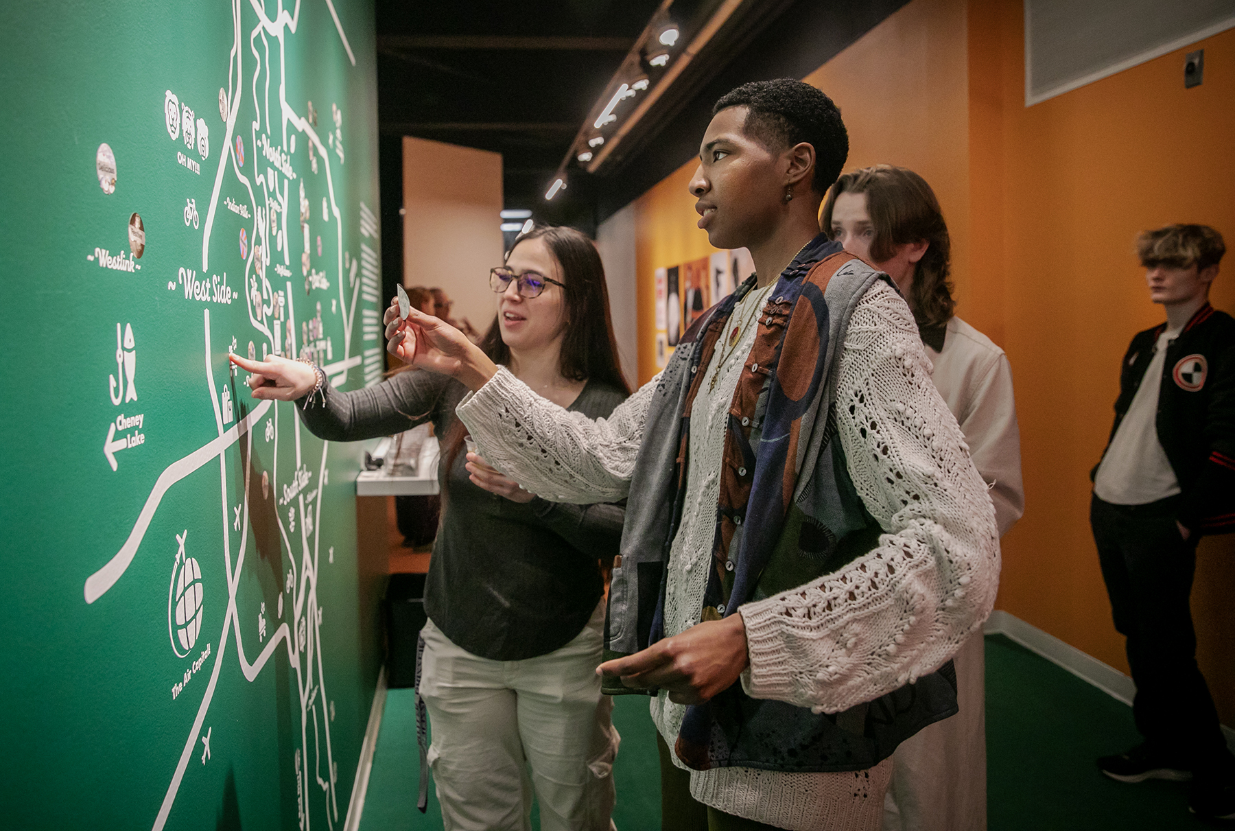 Young people chat and place stickers on a wall map.