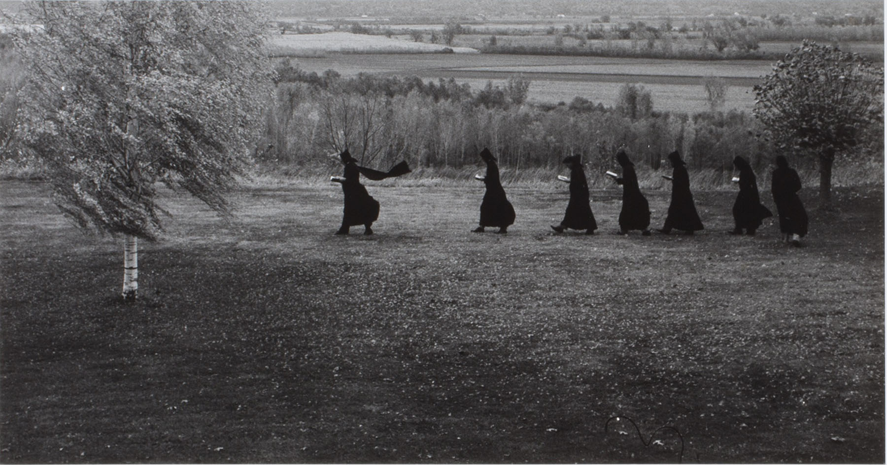 Witches run across a field.