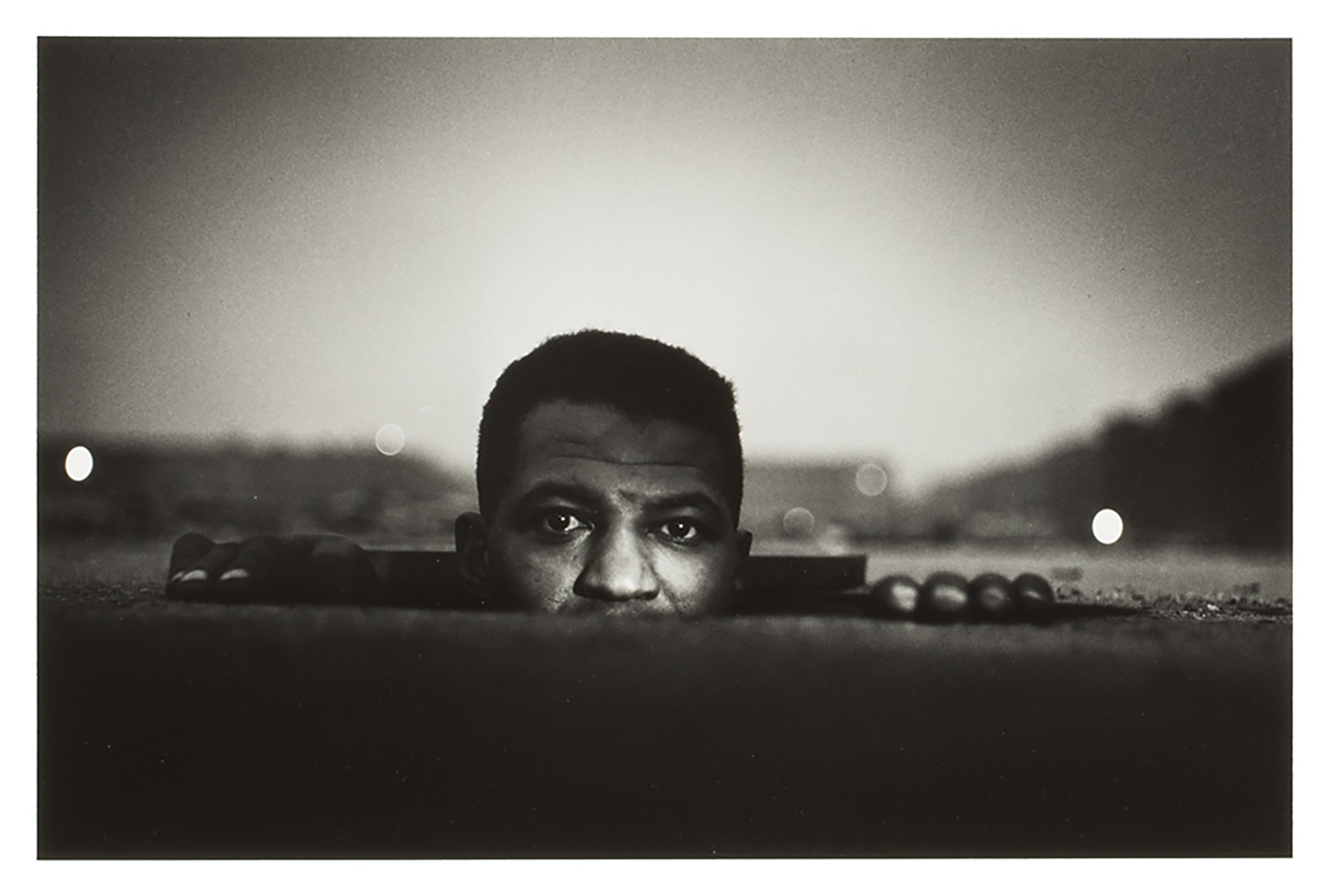 Black and white photo of a man rising out of a hole in the ground.