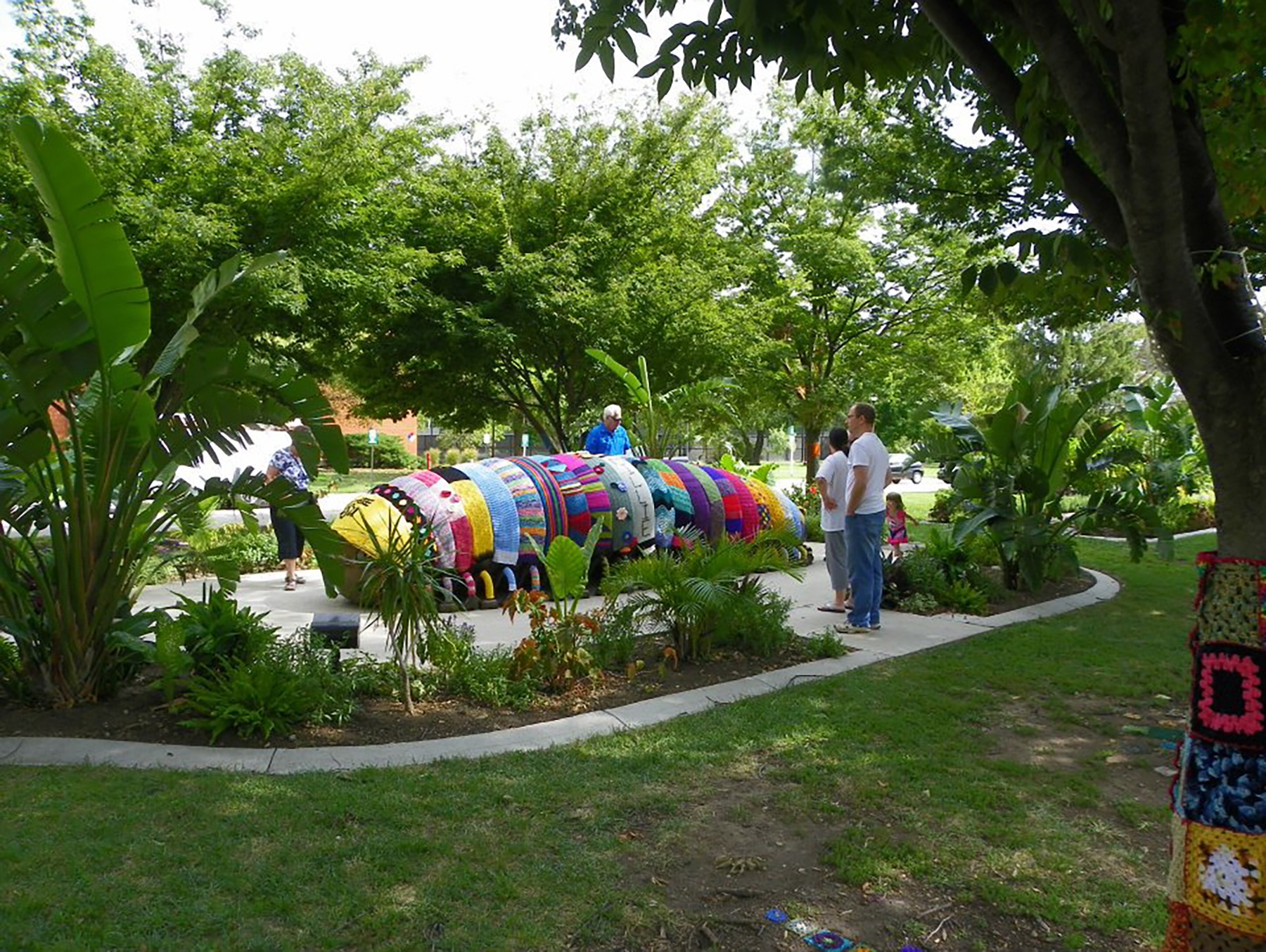 Visitors look at a bronze millipede statue covered with colorful fiber handwork.