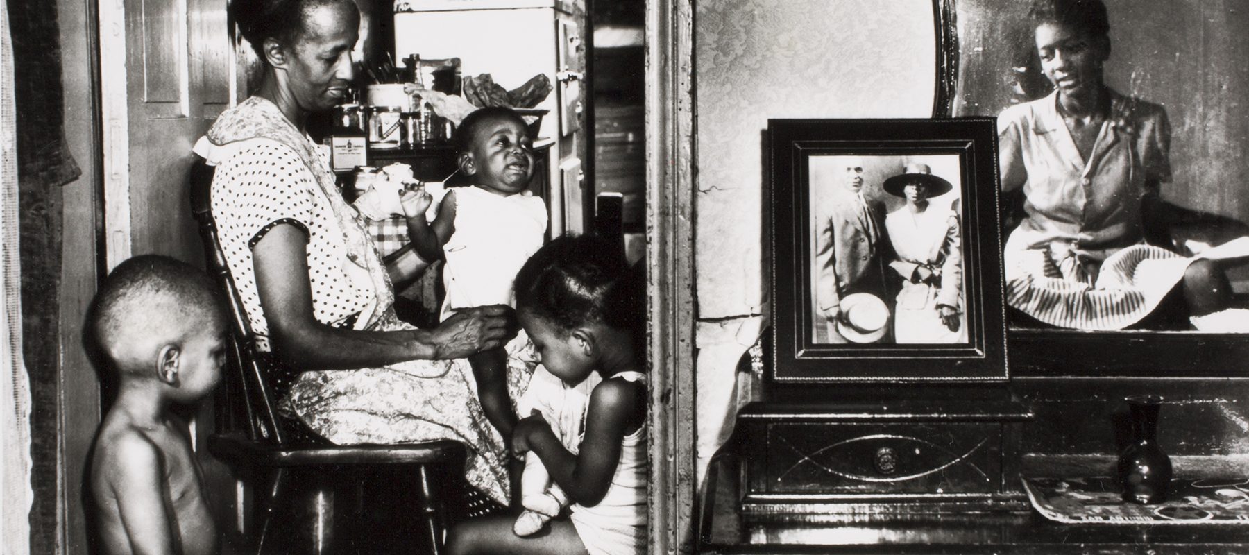 A mother and older sister feed younger children.