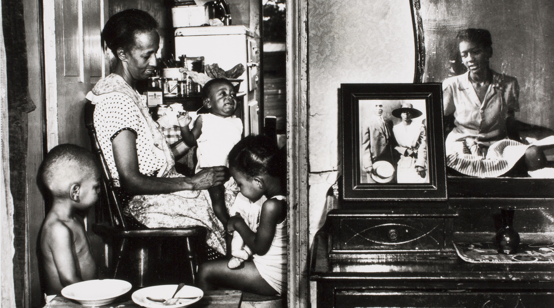 A mother and older sister feed younger children.